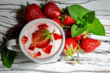 strawberry yogurt in a white cup with mint and fresh strawberries