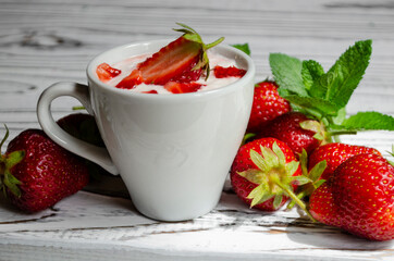 strawberry yogurt in a white cup with mint and fresh strawberries