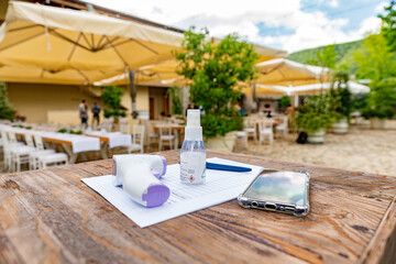 Pontelatone, Italy. June 7th, 2020. Coronavirus anti-contagion control measures at the entrance of a restaurant. Forehead Non Contact Infrared Thermometer. Temperature check. Hand sanitizer bottle.