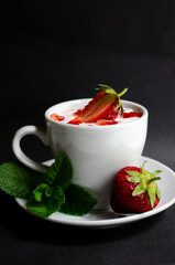 strawberry yogurt in a white cup with mint and fresh strawberries