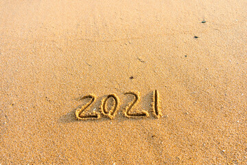2021 year handwritten on sandy beach natural outdoors background.