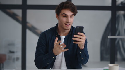 Smiling business man making video call on smartphone in office.