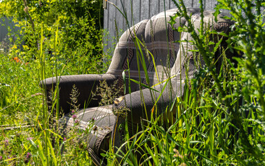 An old sofa stands in the grass in the open air.