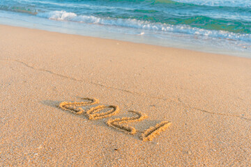 2021 year handwritten on sandy beach natural outdoors background.