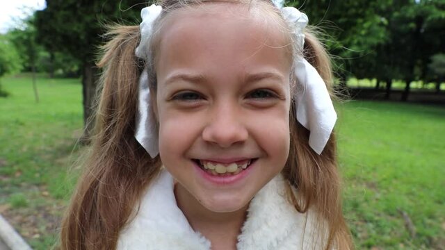 Close-up little beautiful girl smiles in spring park. HD video without sound.