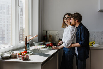 Beautiful young woman and man hugging and kissing in the kitchen.