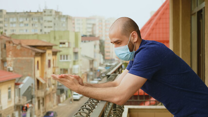 Cheerful man with mask clapping on balcony in support of doctor on fight against coronavirus.