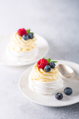 Delicious Pavlova cake with whipped cream and fresh berries on white plate. Stone background. Selective focus