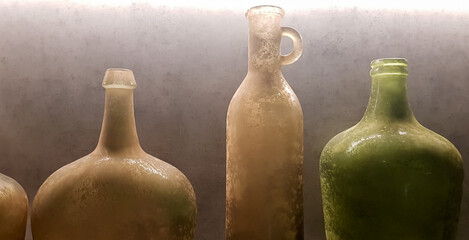 large vintage vases or jugs of colored glass as decoration elements in a modern interior near a gray concrete wall. Decoration of an apartment or house.