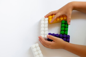 Obraz premium children`s plastic constructor on a white background with children`s hands