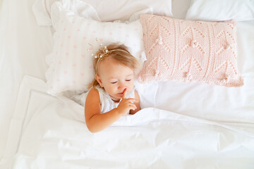 Fototapeta na wymiar little girl sleeping in bed in bedroom with crown. Princess birthday party. 