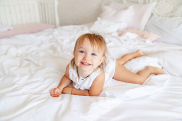 little girl on bed in bedroom and laughs. happy childhood.