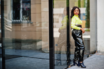 Portrait of young beautiful african american fashion model woman, wear in green top and black shiny wet look pants.
