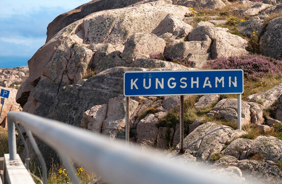 Blaues Ortsschild der schwedischen Stadt Kungshamn vor einer Kulisse aus Granit