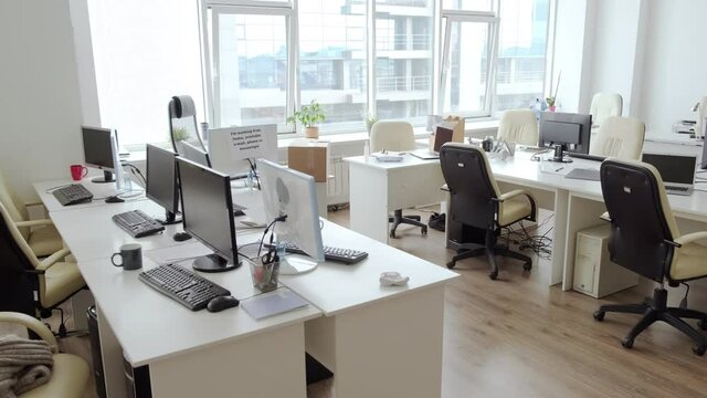 Dolly-out shot of desks and computers in empty office amidst covid-19 pandemic
