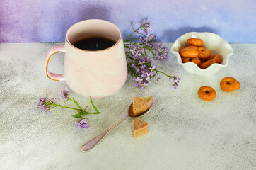 Ceramic coffee cup, bagels and lilac flowers on the table. Healthy breakfast in the morning