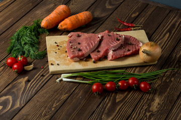 raw meat on a cutting board. beef steak with herbs, cherry tomatoes,