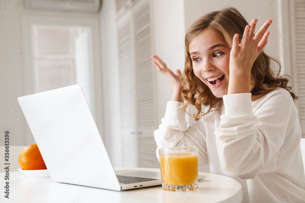 Wall mural Photo of cheerful girl taking video call on laptop and showing hands