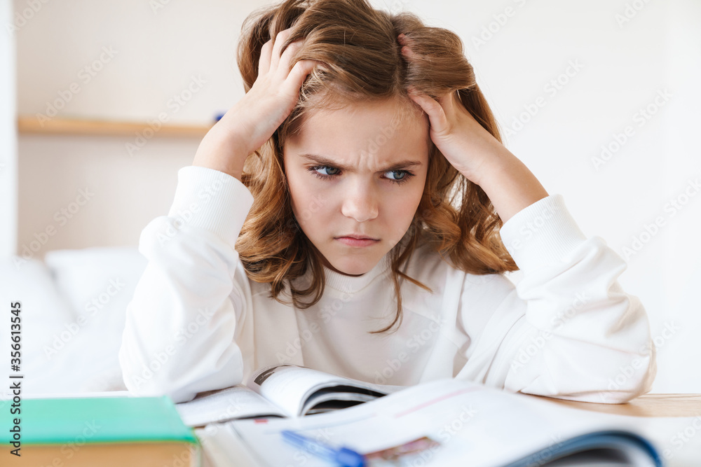 Wall mural photo of caucasian furious girl grabbing her head while doing homework