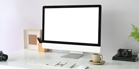 A blank screen computer monitor is putting on a white working desk surrounded by office equipment.