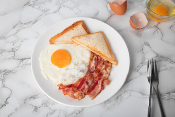 Breakfast with sunny side eggs, bacon and toast bread on a plate