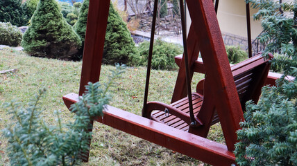 Fototapeta na wymiar A backyard swing is ideal for relaxing. Garden old wooden swing in the backyard of a rural house.