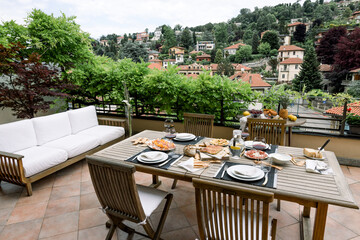 dining table with wooden chairs set on the terrace with beautiful italian landscape. food concept