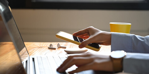 Cropped image of an office woman is charging a smartphone with a wireless charger while typing on a...
