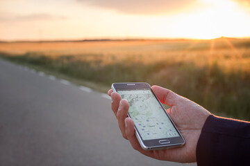 man with a smartphone in hand using the GPS app at sunset