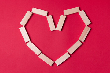 jenga wooden blocks in form of heart with copy space on red colored paper background