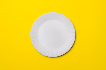 white eco-friendly paper plate on yellow colored paper background. top view. mock-up