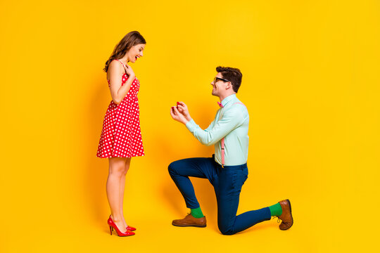 Full body profile photo of pretty lady handsome guy couple proposing girlfriend stand one knee hold diamond ring box wear red dress shirt bowtie isolated yellow bright color background