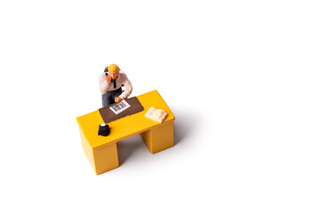 Obraz premium Miniature businessman behind desk at the office