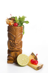 tiki cocktail decorated with pineapple and lemon and cherry with white background
