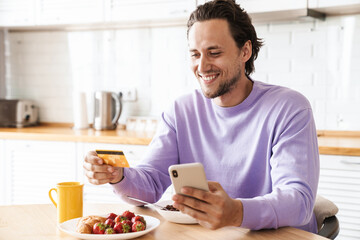 Attractive young man sitting at the kitchen table