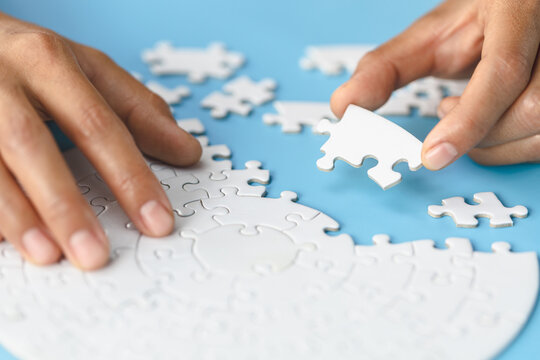 White jigsaw in the hands of humans, The correct solution. Teamwork, Solving and completing the task. Last piece of jigsaw puzzle. Assembling  jigsaw puzzle pieces.