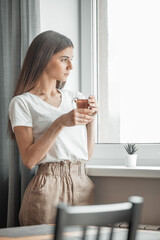 Beautiful woman drinking morning tea behind window