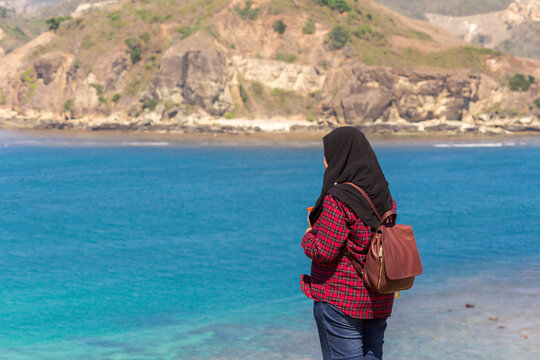 a young woman looking at the beauty of the coast and sea from the top of the hill