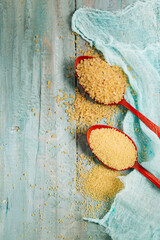 couscous and bulgur in a red spoon on a blue background