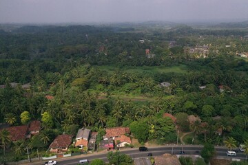 Fototapeta na wymiar natural aerial drone bird view day shot of the sea shore with a road, beautiful villas and green forest trees. Pitiwella, Sri Lanka