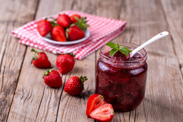 Homemade delicious strawberry jam and strawberry on a rustic wooden table
