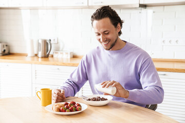 Attractive young man sitting at the kitchen table