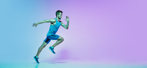 Fototapeta na wymiar In jump. Portrait of young caucasian man running, jogging on gradient studio background in neon light. Professional sportsman training in action and motion. Sport, wellness, activity, concept. Flyer.