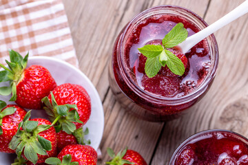 Homemade delicious strawberry jam and strawberry on a rustic wooden table