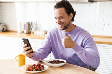 Attractive young man sitting at the kitchen table