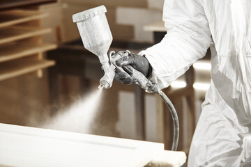 Close-up of industrial worker using paint gun or spray gun for applying paint, airless spraying.