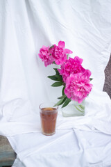 glass with tea and a bouquet of flowers on a white vintage background. flowers red peonies