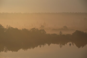 The river Bank in a yellow fog colored by sunlight at dawn.Russia
