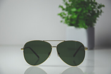 Front view of black sunglasses with golden rim on white table