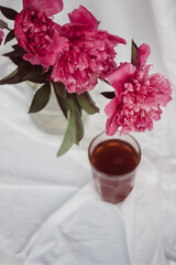 glass with tea and a bouquet of flowers on a white vintage background. flowers red peonies